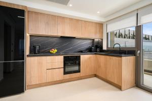 a kitchen with black appliances and wooden cabinets at Majo Luxury Villas Panoramic Sea View Retreat with Heated Private Pools & Gym & Sauna in Agia Pelagia