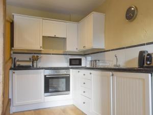 a kitchen with white cabinets and a microwave at Kildale Barn in Kildale +10 photos