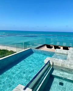 a swimming pool with a view of the ocean at Studio Luxo Frente Mar NT 311 in Maceió