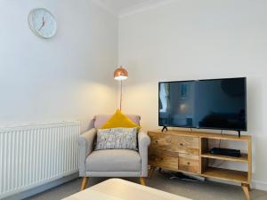 a living room with a chair and a large tv at Smugglers Neuk- cosy flat for 2 in Cellardyke
