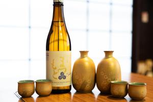 a bottle of wine sitting next to four vases at The Sake Kura villa in Hakuba