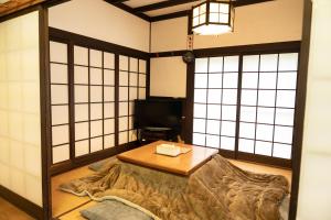 a room with a bed and a table and windows at The Sake Kura villa in Hakuba