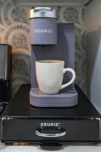 a coffee maker with a cup on top of a microwave at - 5-Min Walk To Metro - Free Prking - Escape in Alexandria