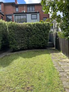 a hedge in front of a house with a yard at Renovated home in central location in Sandy Bay