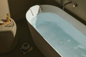 a bath tub filled with blue water next to a table at Cape of Senses in Torri del Benaco +45 photos