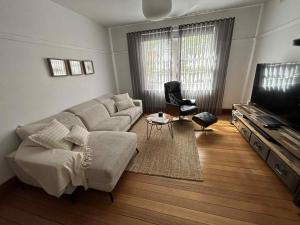a living room with a couch and a tv at Renovated home in central location in Sandy Bay