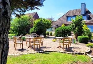 een terras met tafels en stoelen voor een huis bij Moderne Ferienwohnung mit Sonnenterrasse & Gartenblick - Strandnah und hohem Schlafkomfort in Scharbeutz