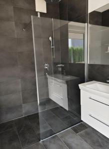 Un baño con ducha, lavabo y espejo. en ALMMONTE LIGNUM Lodge, en Wagrain 8 fotos más