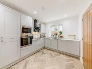 a white kitchen with white cabinets and a wooden floor at Sandpiper Rest - Uk46781 in Ellington