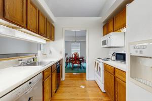 una cocina con armarios de madera y electrodomésticos blancos en Birch Tree Lane - Unit 314, en Bar Harbor