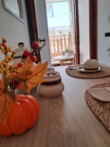 Una mesa de comedor con una calabaza y hojas de otoño. en Prisciò, en Melendugno