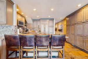 eine Küche mit Holzschränken und eine Bar mit Lederstühlen in der Unterkunft Lake Chelan Shores - Beachfront Splendor 12-5 in Lakeside