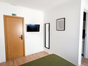 a room with a door and a television on a wall at VT Guest House in Setúbal
