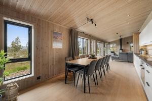 a kitchen and dining room with a table and chairs at Sentralt plassert hytte, alt i gangavstand in Flå