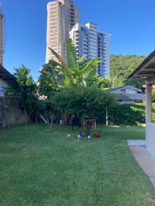 Drei Kinder spielen im Gras in einem Hof mit Gebäuden in der Unterkunft Casa 183 in Itajaí