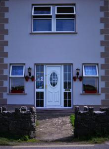 uma casa branca com uma porta branca e janelas em Doolin House em Doolin