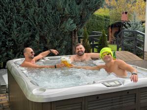 three men in a hot tub with drinks in it at Cazare Colibita - Casa Lipan cu jacuzzi, foișor și loc de joacă in Colibiţa