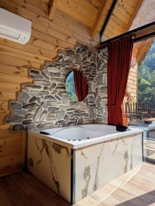 a bath tub in a room with a stone wall at Walnut Bungalow in Çamlıhemşin
