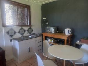 - une cuisine avec une table blanche, des chaises et un évier dans l'établissement Ormonde guesthouse, à Pretoria