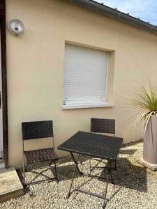 two chairs and a table in front of a building at Charmant studio près de Sancheville - 27 m² - 2 pers in Bercis
