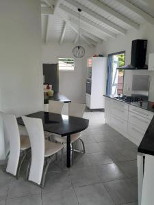 Una cocina con una mesa negra y sillas blancas. en Appartement spacieux à Morne-à-l'Eau, 80 m², piscine privée, en Brion