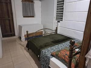 a bed sitting in a room with a table at Bungalow cosy à Sainte-Anne avec jardin in Sainte-Anne