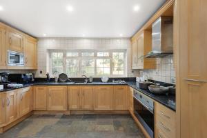 a large kitchen with wooden cabinets and a window at Garden Parking WiFi Near Sky Elstree Studios in Elstree