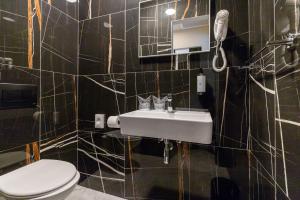 a black tiled bathroom with a sink and a toilet at Hotel Emaus in Novigrad Istria