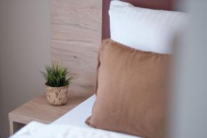 Una almohada en una cama con una planta en una mesa. en sQuare Hotel, en Frankfurt