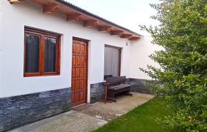 a white house with a wooden door and a bench at departamento por dia ruta 41 3 in Los Antiguos