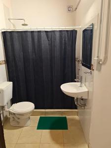 a bathroom with a black shower curtain and a toilet and sink at departamento por dia ruta 41 3 in Los Antiguos
