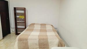 a bed in a white room with a blanket on it at departamento por dia ruta 41 3 in Los Antiguos