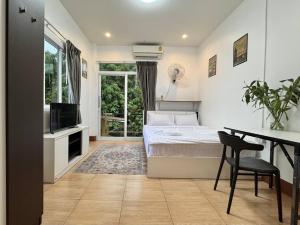 a bedroom with a bed and a table and a television at PROpaganda Guest House in Thongsala +7 photos
