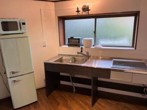 a kitchen with a sink and a refrigerator and a window at 鶴岡市中心地ゲストハウス in Tsuruoka +1 photo