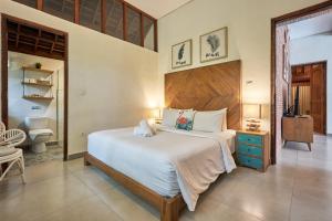 チャングーにあるCasa Ola Villa Pererenanの木製のヘッドボードが付いた大きなベッドのある寝室