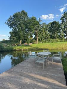 a table and chairs on a dock next to a river at Arimaičių kaimo sodyba in Arimaičiai