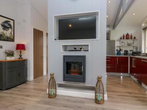 a living room with a fireplace and a flat screen tv at 5 Waterside Wood in Troutbeck Bridge