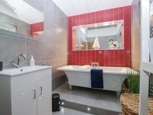 a bathroom with a tub and a sink and red tiles at 5 Waterside Wood in Troutbeck Bridge +38 photos
