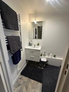 a white bathroom with a sink and a mirror at Charmant studio à Paris in Courbevoie +11 photos