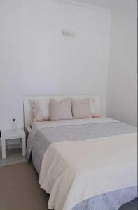 een witte slaapkamer met een groot wit bed met kussens bij Maresia Baleal House in Baleal