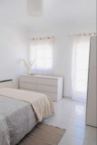 een witte slaapkamer met een bed en twee ramen bij Maresia Baleal House in Baleal +3 foto's