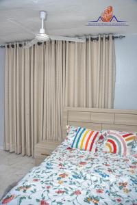 a bedroom with a bed with a comforter and curtains at Ranscilla Homes & Apartments in Tema