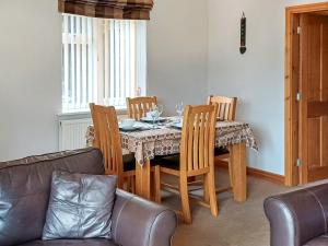 a dining room with a table with chairs and a couch at Bwthyn Bwlch in Denbigh