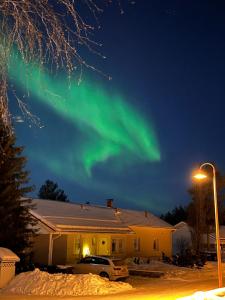 an aurora in the sky above a house at Arctic Circle Luxury House - close to Santa's Village in Rovaniemi