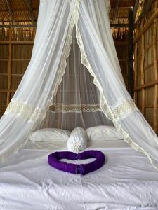 a bed with a canopy with a purple ribbon on it at Humble Homestay in Besir