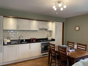 a kitchen with white cabinets and a table and a dining room at Cottage 7 - Skye Cottage in Fort Augustus