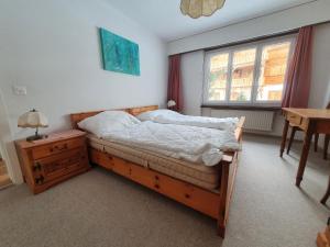 a bedroom with a bed and a desk and a window at LAAX Homes - Maighels 8-9 in Laax-Murschetg