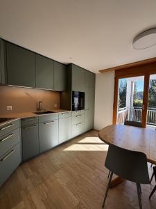 a kitchen with a table and a dining room at LAAX Homes - Val Mulin 14,2 in Laax-Murschetg