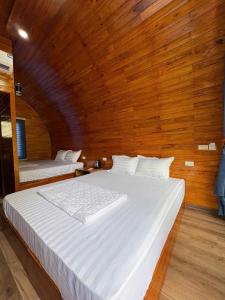 a large white bed in a room with wooden walls at Trang an mountain view bungalow in Nguyên Ngoại