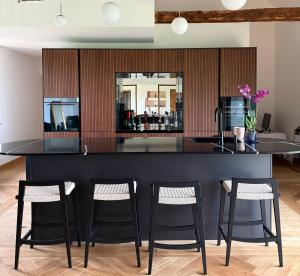 a kitchen with a black island with three bar stools at Le Secret in Lusigny +5 photos